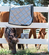 Dressage saddle pad and polo wraps on a white vinyl fence. Two horses are in the background with one peaking it's head through the fence. Gray Dressage Bundle with Fly Veil, Polo Wraps and a Dressage saddle pad. Gray in color with semi shiny material.