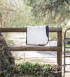White Dressage saddle pad and polo wraps on a natural wood fence. Trees are in the background. White Dressage Bundle with Fly Veil, Polo Wraps and a Dressage saddle pad. White in color with semi shiny material.